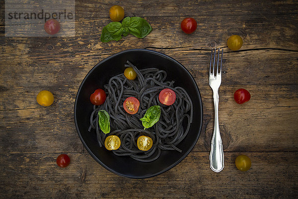 Schale Spaghetti al Nero di Seppia mit Tomaten und Basilikumblättern