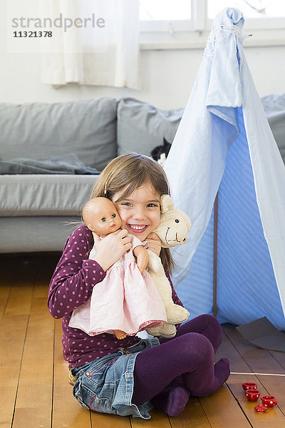 Porträt eines glücklichen kleinen Mädchens mit ihren Spielsachen zu Hause