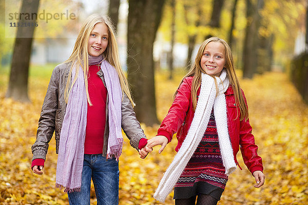 Zwei glückliche Mädchen Hand in Hand im Herbst