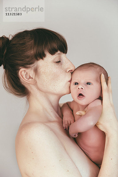 Nackte Mutter küsst ihr neugeborenes Baby
