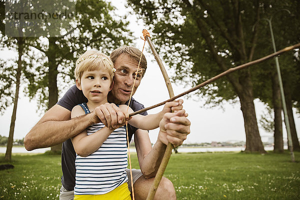 Vater und Sohn spielen mit selbstgebasteltem Pfeil und Bogen