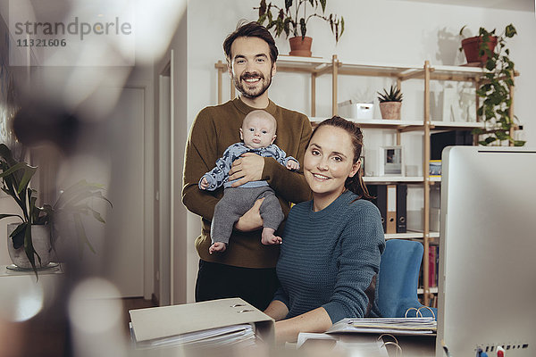 Porträt von lächelndem Vater und Mutter mit Baby im Home Office