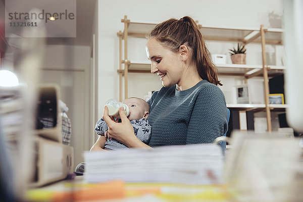Frau füttert ihr Baby im Home-Office