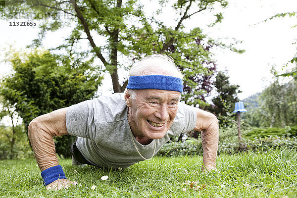 Senior Mann macht Liegestütze für Fitnesstraining im Garten