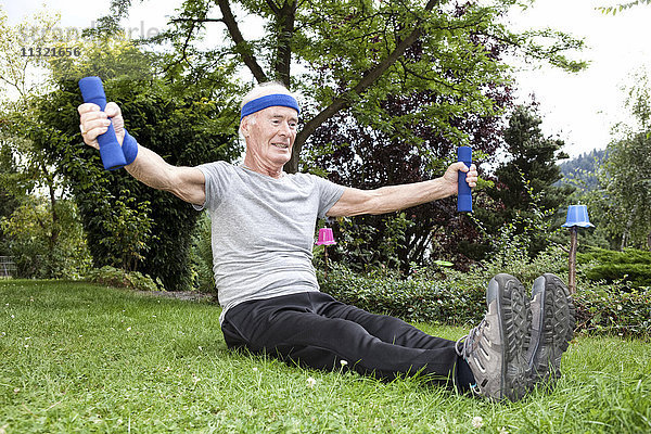 Senior Mann beim Fitnesstraining mit Kurzhanteln im Garten