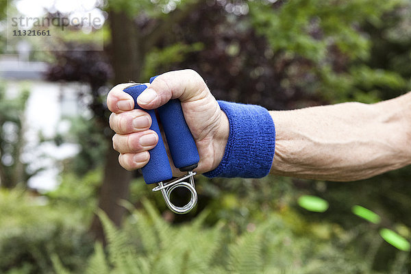 Senior Mann beim Fitnesstraining mit Greifer im Garten