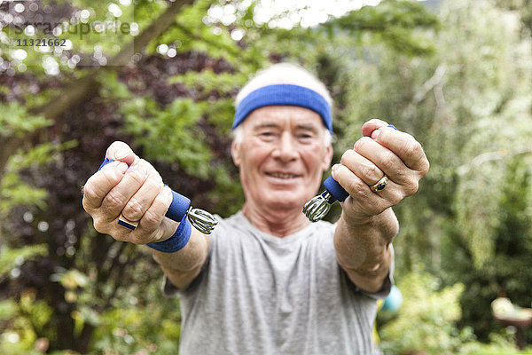 Senior Mann beim Fitnesstraining mit Greifer im Garten