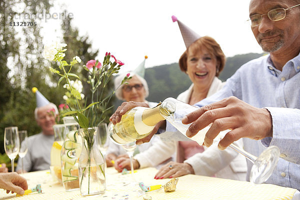 Senioren feiern  Mann gießt Champagner ins Glas