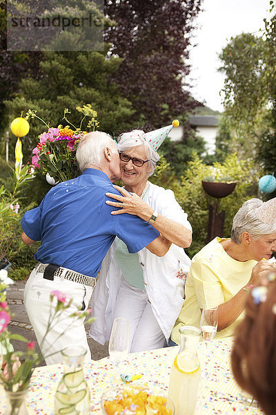 Senior Mann küsst ältere Dame bei Geburtstagsfeier