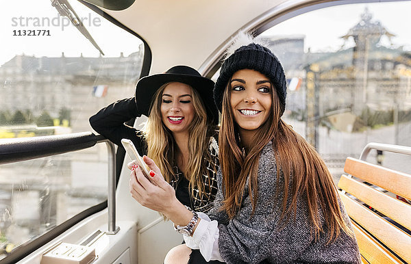 Frankreich  Paris  zwei lächelnde Frauen mit Handy im Reisebus