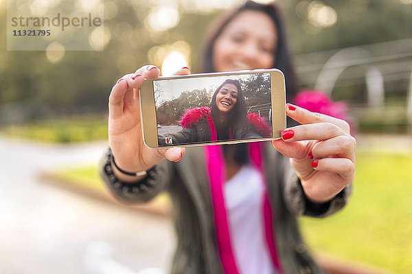 Junge Frau  die im Herbst einen Selfie in einem Park macht.