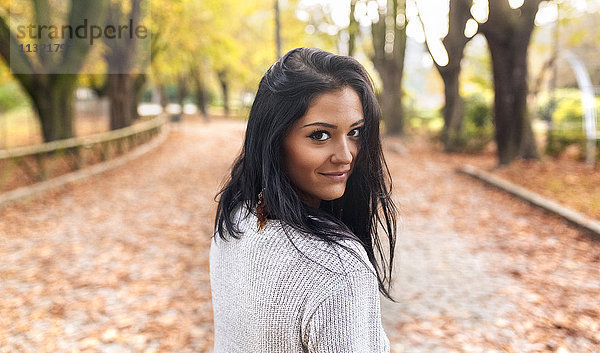 Porträt einer lächelnden jungen Frau in einem Park im Herbst