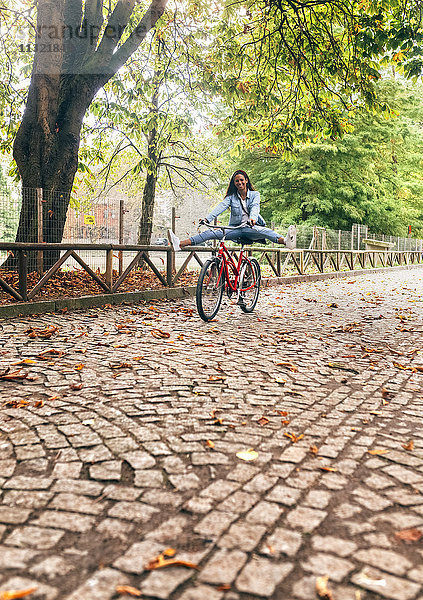 Glückliche junge Frau beim Radfahren im Park