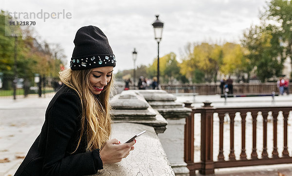 Frankreich  Paris  lächelnde junge Frau auf dem Handy