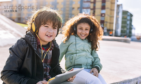 Zwei Kinder beim Musikhören mit Kopfhörer und Tablett