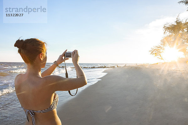 Frau am Strand fotografiert mit ihrer Kamera