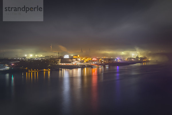 Deutschland  Hamburg  Blick auf den Hafen mit beleuchtetem Musiktheater im Nebel bei Nacht