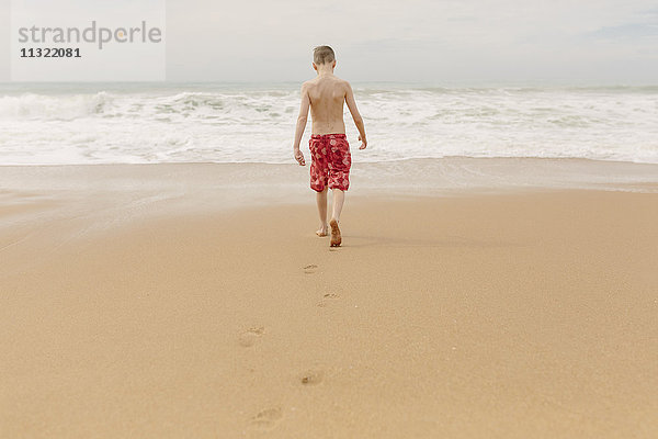 Junge  der am Strand spazieren geht