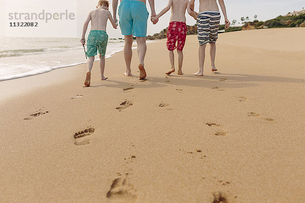 Vater und Söhne gehen am Strand spazieren