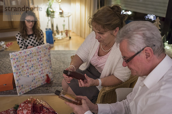 Schenken am Weihnachtsabend  Großeltern beim Betrachten von Flaschen