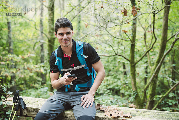 Portrait eines lächelnden Wanderers mit Smartphone in der Natur