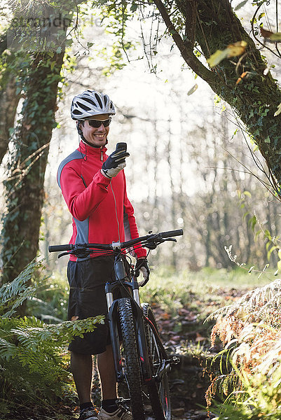 Mountainbiker mit Smartphone im Wald
