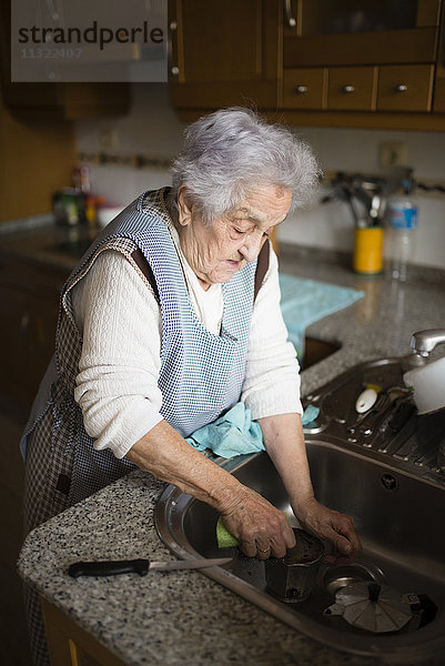 Seniorin beim Geschirrspülen in der Küche