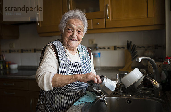 Seniorin beim Geschirrspülen in der Küche