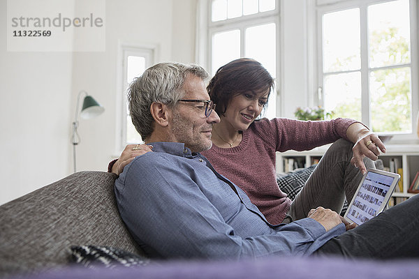 Reife Paare zu Hause auf dem Sofa-Sharing-Tablett