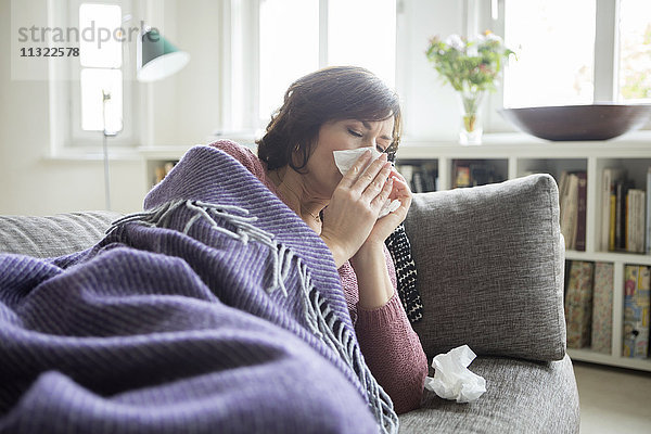 Frau mit einer Erkältung auf dem Sofa liegend