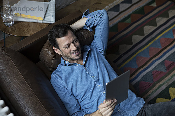 Mann auf der Couch liegend  mit digitalem Tablett