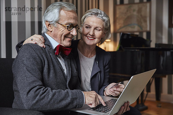 Glückliche Seniorenpaare beim Online-Shopping zu Hause