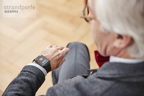 Senior Mann überprüft medizinische Daten auf smartwatch