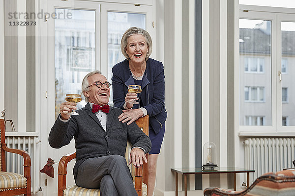 Glückliches Seniorenpaar trinkt Champagner zu Hause