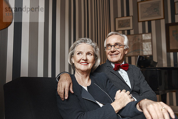 Glückliches älteres Paar auf der Couch sitzend