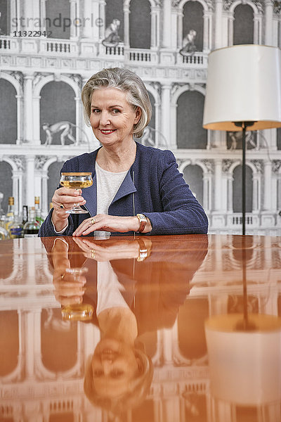 Porträt einer älteren Frau  die ein Glas Champagner trinkt.