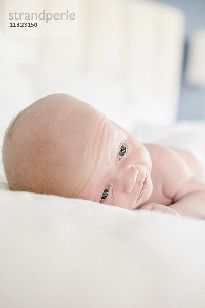 Ein kleines Baby  das auf einem Bett liegt.