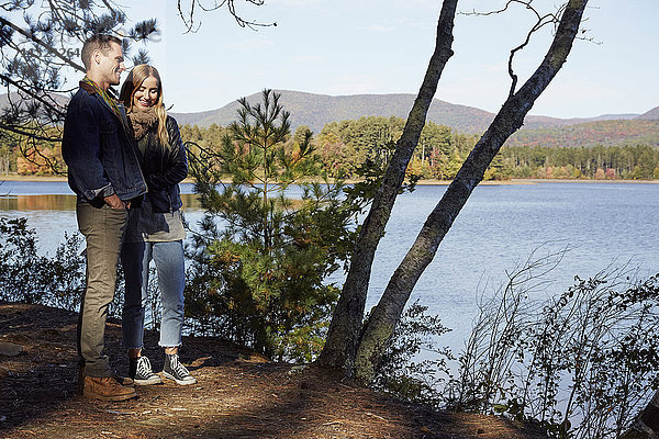 Zwei Personen am Ufer eines Sees im Herbst.