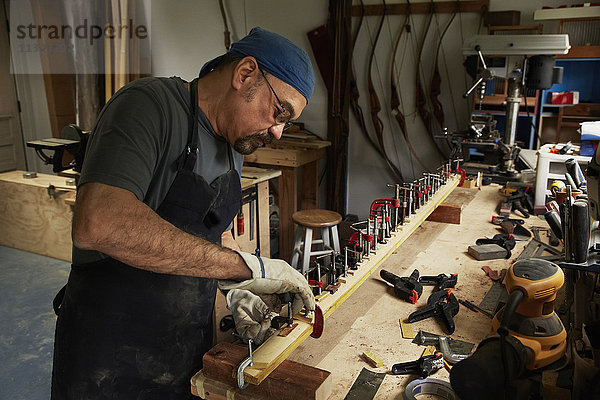 Ein Bogenschütze  ein geschickter Mann  der einen Bogen herstellt  in seiner Werkstatt.