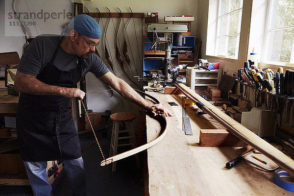 Ein Bogenschütze  ein geschickter Mann  der einen Bogen herstellt  in seiner Werkstatt.