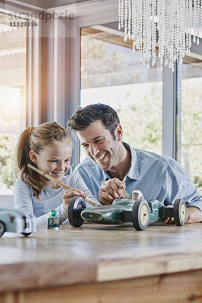 Vater und Tochter malen einen Spielzeug-Rennwagen