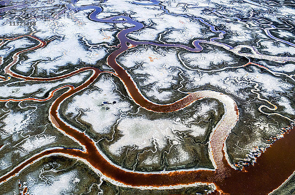 Luftaufnahme der Landschaft  der gewundenen Wasserkanäle und der Salzpfannen mit weißen Salz- und Mineralvorkommen bei Alvisio.