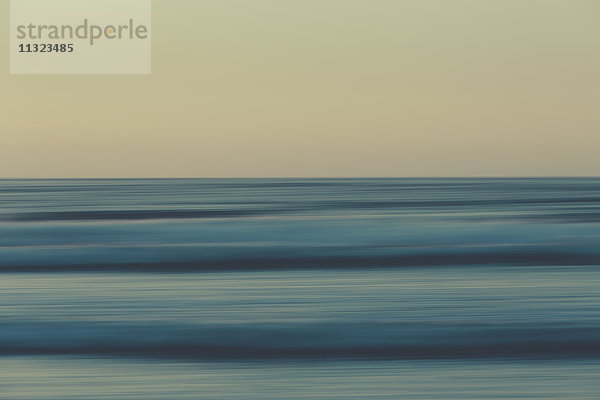 Meereswellen und der Blick vom Strand in der Abenddämmerung auf den Horizont über dem Meer.