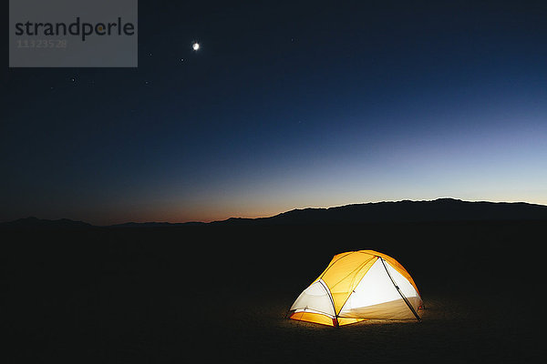 Beleuchtetes Zelt in riesiger Wüste in der Abenddämmerung  Schwarze Steinwüste  Nevada