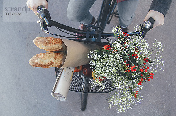 Mann mit Äpfeln  Blumenstrauß  Zeitung und Baguette im Fahrradkorb