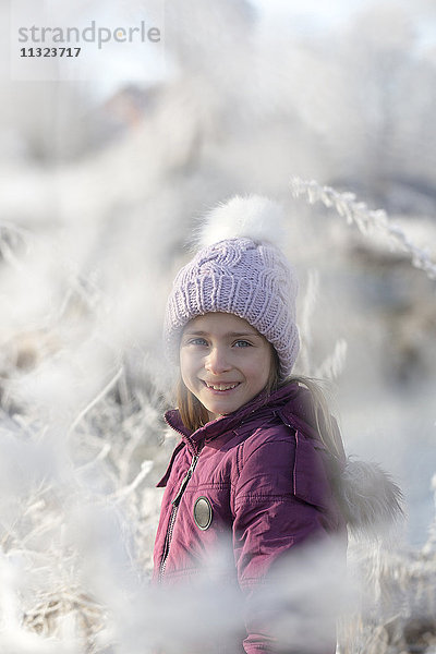 Porträt eines glücklichen Mädchens mit Pudelmütze im Winter