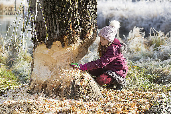 Mädchen berührt Baumstamm im Winter
