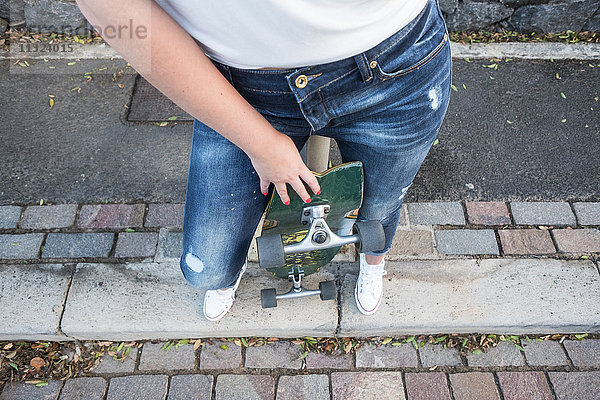 Junge Frau mit Skateboard  Teilansicht