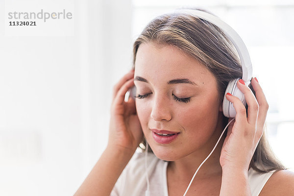 Junge Frau mit geschlossenen Augen Musik hören mit Kopfhörer