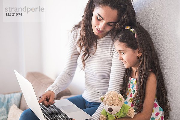 Teenager Mädchen und ihre kleine Schwester mit Laptop